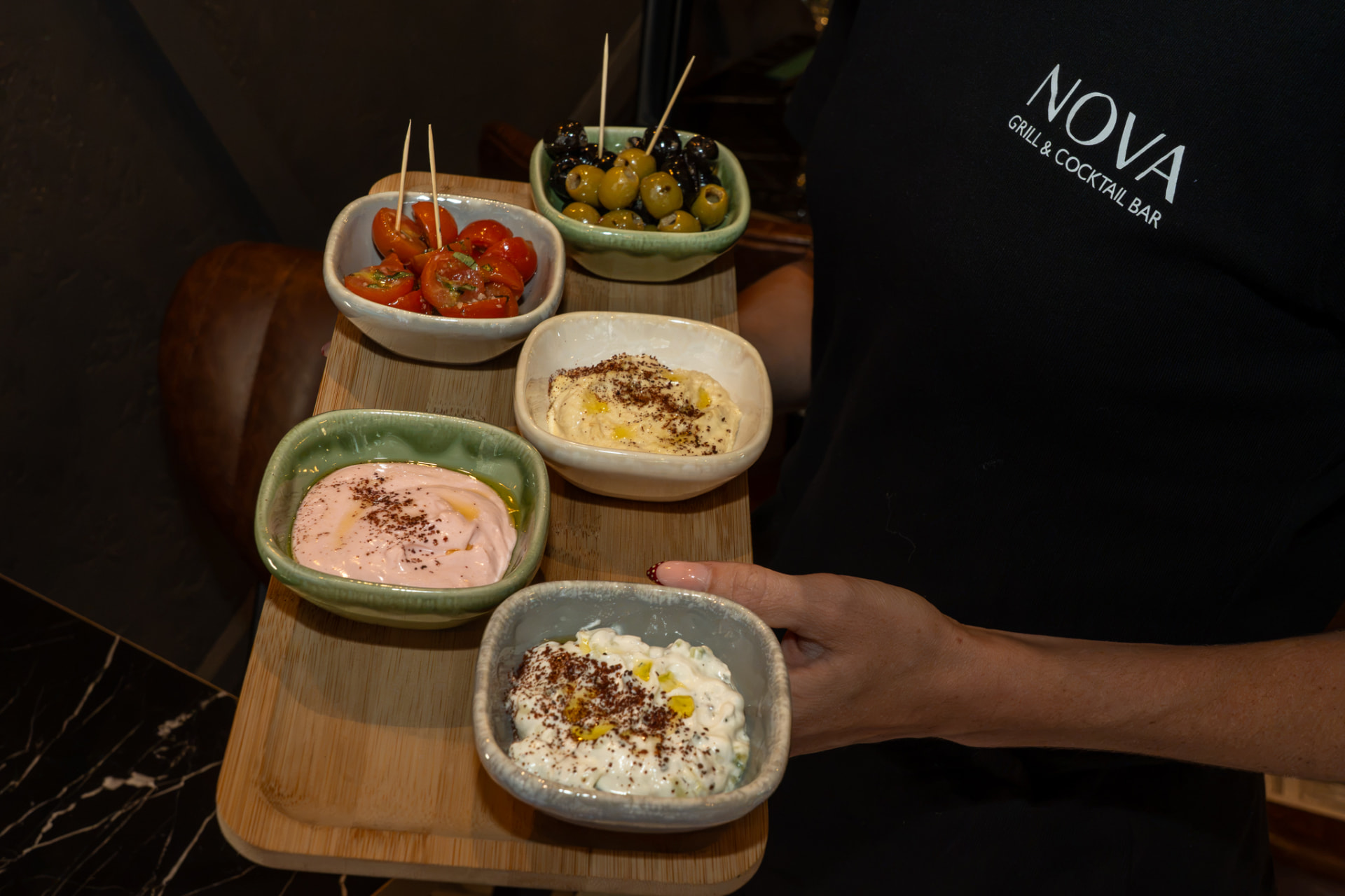 A Nova cold starter board with dips, olives and tomatoes